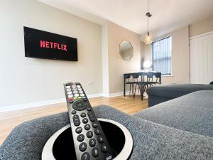 control remoto sentado en un sofá en una sala de estar en 2 Bedroom house 10 mins to City Centre & Albert Dock, en Liverpool
