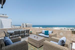 um pátio com cadeiras e mesas de vime e a praia em « The Sea » Penthouse with sea view by Host Eretz em Tel Aviv