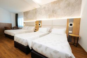 2 Betten in einem Hotelzimmer mit weißer Bettwäsche in der Unterkunft Hotel Everest in Trient