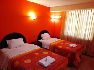 two beds in a room with orange walls at Colca Andina Inn Chivay in Chivay