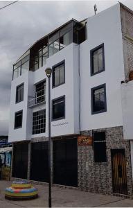 a white building with black windows and a street light at Colca Andina Inn Chivay in Chivay