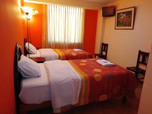 two beds in a hotel room with orange walls at Colca Andina Inn Chivay in Chivay