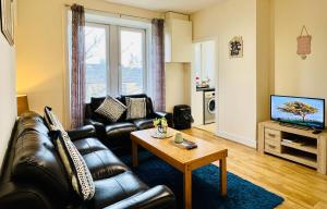a living room with a leather couch and a coffee table at Cosy Apartment Glasgow Airport in Paisley