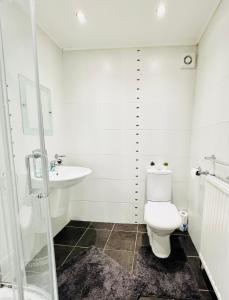 Baño blanco con aseo y lavamanos en Cosy Apartment Glasgow Airport, en Paisley