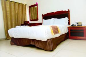 伊巴丹的住宿－Classicus Inn & Apartments，一间卧室配有一张大床和一部电话