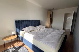 Schlafzimmer mit einem großen Bett mit blauem Kopfteil in der Unterkunft 2 room Apartment, terrace, new building Moruše in Prievoz
