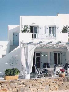 una casa blanca con sillas y una mesa frente a ella en Dolce Vita Waterfront Villa, Logaras, Paros, en Kampos