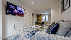 een woonkamer met een bank en een tv aan de muur bij Morden 2-Bed House in Canary Wharf London in Londen