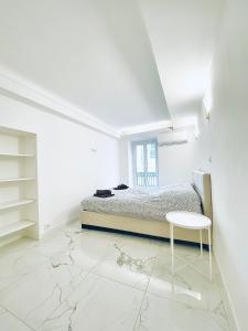 ein weißes Schlafzimmer mit einem Bett und einem Tisch in der Unterkunft T3 carré d’or plein centre in Nizza