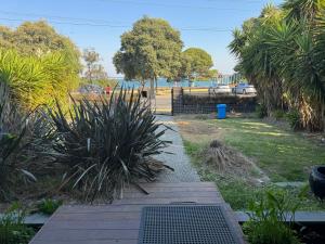 Geelong Luxury Beach K Villa في North Shore: حديقة بها ممشى خشبي وبعض النباتات