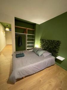 Cama grande en habitación con pared verde en Le Wimbledon en Chalon-sur-Saône