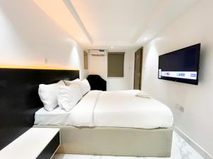a bedroom with a white bed and a flat screen tv at luxe apartments in Lagos