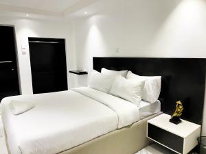 a bedroom with a white bed with a black headboard at luxe apartments in Lagos