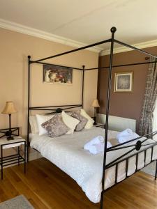 a bedroom with a black canopy bed with pillows at Bealkelly Country House in Killaloe