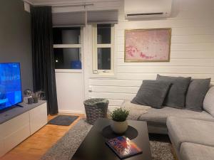 uma sala de estar com um sofá e uma televisão em På toppen av Tromsøya. Rett ut i naturen! em Tromsø