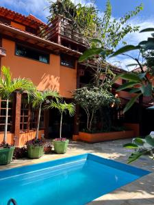 a house with a swimming pool in front of a building at Pousada Alforria in Búzios