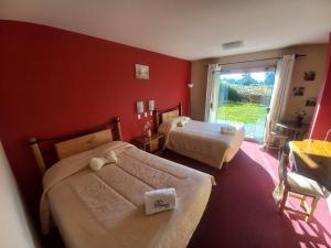 1 dormitorio con 2 camas y pared roja en Hotel Pumakala, en Puno
