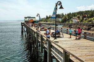 um grupo de pessoas em pé em um cais perto da água em Yellow Door Suite em Campbell River