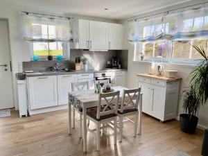 eine Küche mit weißen Schränken und einem Tisch und Stühlen in der Unterkunft Wohnstudio für bis zu 1-4 Personen nahe Bodensee in Stockach