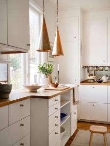 une cuisine avec des placards blancs et un comptoir avec un tabouret dans l'établissement The Royal home - Liseberg / Svenska Mässan, à Göteborg