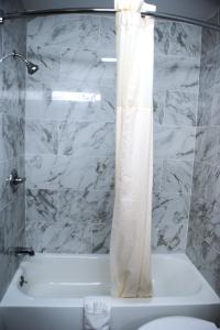 baño con bañera blanca y cortina de ducha en Van Buren Inn, en Van Buren
