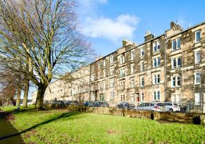 un gran edificio con un árbol delante en Cosy Apartment Glasgow Airport, en Paisley