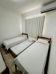 três camas num pequeno quarto com uma janela em POUSADA BRASÃO em Governador Valadares