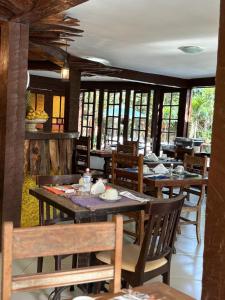 un restaurante con mesas y sillas de madera y ventanas en Pousada Alforria, en Búzios