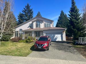 een rode auto geparkeerd voor een huis bij Yellow Door Suite in Campbell River