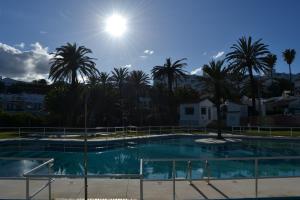 a large swimming pool with palm trees in the background at Beach House Sotogrande - Torreguadiaro in San Roque