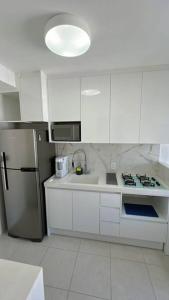 a kitchen with white cabinets and a refrigerator at Chácara Santo Antônio 1 dormitório com sacada in São Paulo