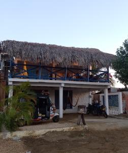 Rincón的住宿－Taida Hostel Rincon del Mar，一座带茅草屋顶的建筑,前面有停车位