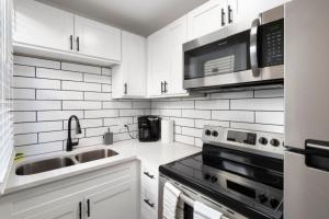 a white kitchen with a sink and a microwave at Luxe Modern Apartment in the Heart of Phoenix (1) in Phoenix