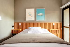 a bedroom with a bed and three pictures on the wall at JQY Beach Flats - 950m da Praia - Garagem subterrânea - Estação de carregamento para veículos elétricos in Juquei