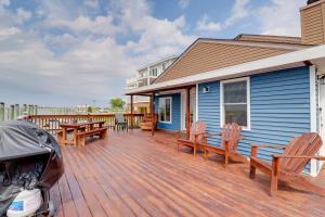 a deck with chairs and tables on a blue house at Oceanfront Milford Home with View and Boat Access in Milford
