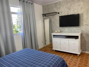 um quarto com uma cama e uma televisão na parede em Residencial Sullivan - Florianópolis - Loft 01 em Florianópolis