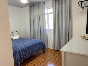 um quarto com uma cama azul e uma janela em Residencial Sullivan - Florianópolis - Loft 01 em Florianópolis