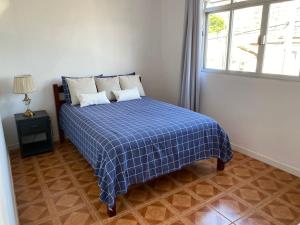 a bedroom with a bed with a blue plaid blanket at Residencial Sullivan - Florianópolis - Loft 01 in Florianópolis