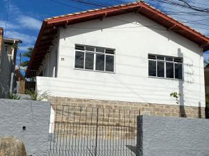 uma casa branca com duas janelas e uma cerca em Residencial Sullivan - Florianópolis - Loft 01 em Florianópolis