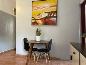 einen Tisch mit zwei Stühlen und ein Gemälde an der Wand in der Unterkunft A cozy one-bedroom in Heron, Djibouti in La Plaine