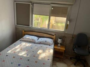 a bedroom with a bed and a chair and two windows at A cozy one-bedroom in Heron, Djibouti in La Plaine