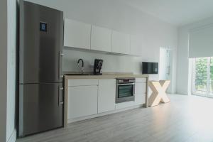 a kitchen with white cabinets and a stainless steel refrigerator at Apartment Gdynia Centrum SEA 5 min do morza in Gdynia