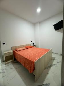 a bedroom with a bed with an orange comforter at Dimora San Nicola in Racale