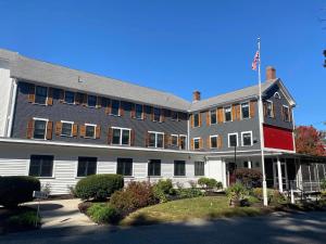 a large white building with a flag on it at Woodbound Inn in Rindge