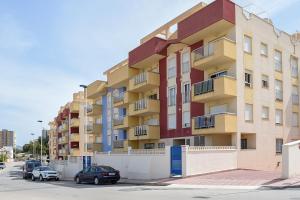 a tall building with cars parked in a parking lot at Apartamento Las Brisas, Atico in Puerto de Mazarrón