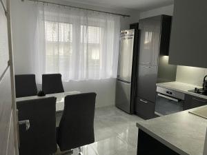 a kitchen with a table with chairs and a refrigerator at Apartament pod Łebą in Charbrowo
