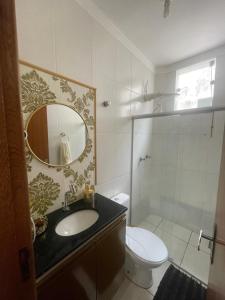 a bathroom with a sink and a toilet and a mirror at Apart Governador Valadares in Governador Valadares
