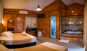 a room with two beds and a bathroom with a tub at Pousada Pitauá in Socorro