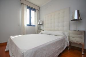 Un dormitorio blanco con una cama grande y una ventana. en Luxury apt in Plaza de España - FREE parking, en Sevilla