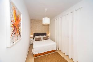 1 dormitorio con 1 cama y una pared con cortinas blancas en Luxury Apartment Chalana, en Playa Honda